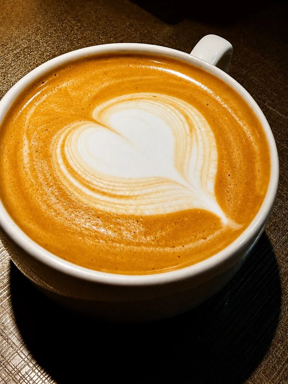 Detalhe de uma xícara de café com leite e latte art em formato de coração.