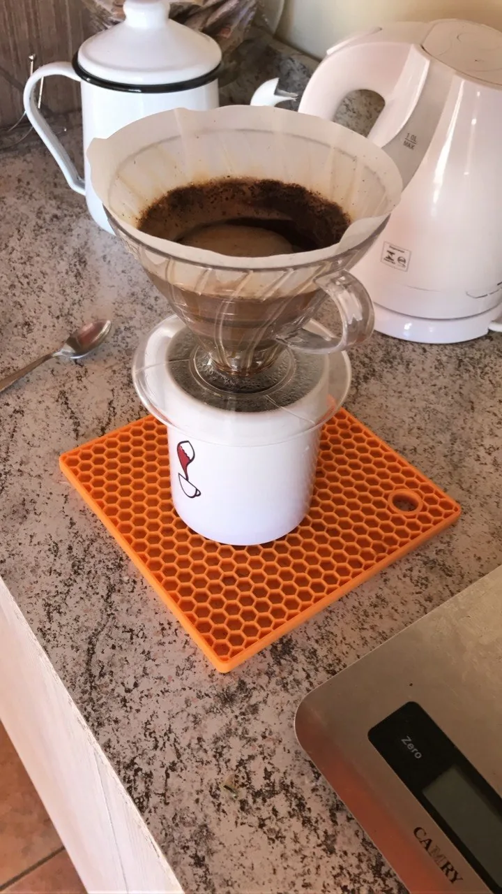 Filtro de papel em um coador de vidro apoiado sobre uma caneca branca com desenho de raposa.