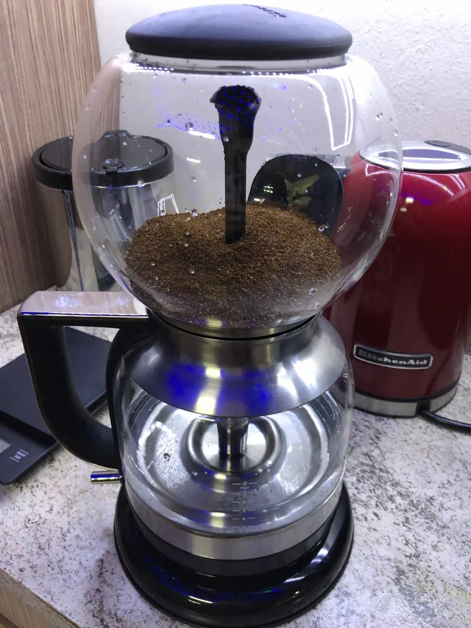 Cafeteira de sifão com dois recipientes de vidro e café na parte superior.