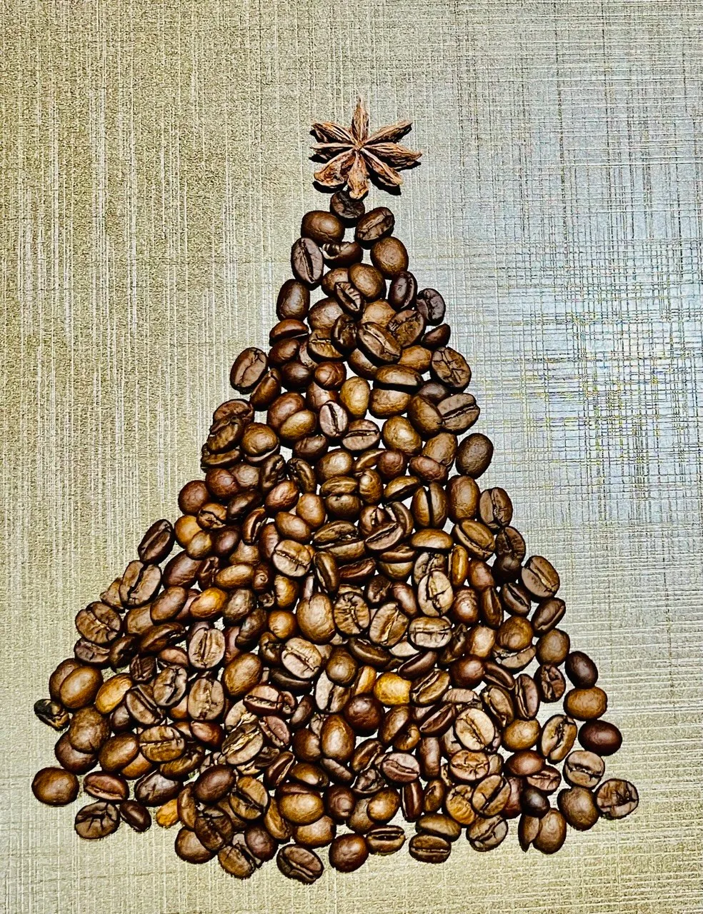 Grãos de café organizados em formato de árvore de Natal, com anis-estrelado no topo.